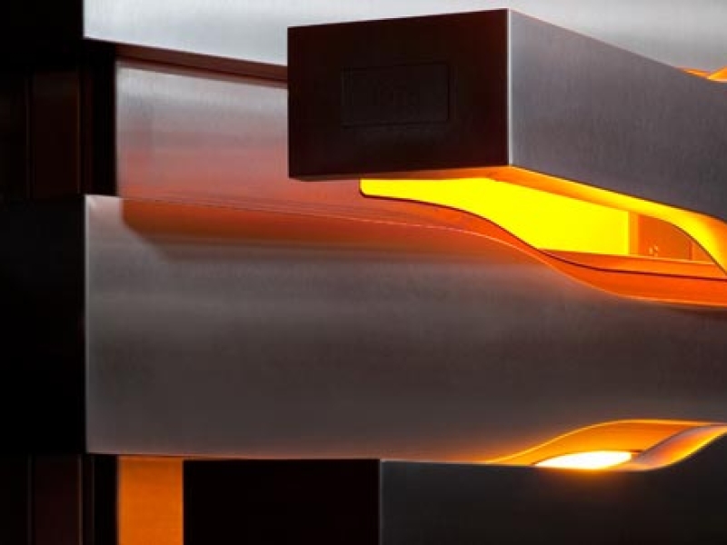 Künstlerische Detail-Aufnahme mit optischem Spiel zwischen oranger Beleuchtung und Dunkelheit (Edelstahl)