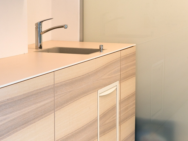 Teeküche mit zertifiziertem Einbau-Brandschutzmüllkipper in Edelstahl (angepasst an Design durch Pulverbeschichtung und integrierte Holzfront)